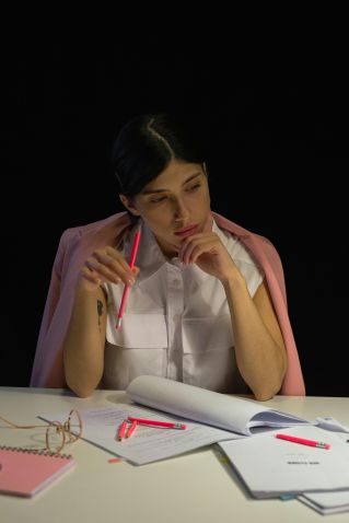 A Woman in White Top with Pink Blazer Holding a Pencil